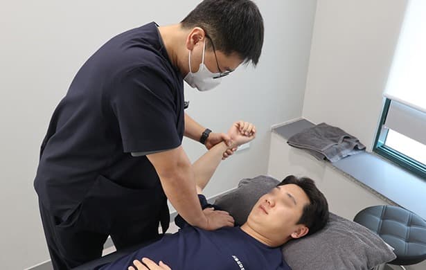 어깨 도수치료 장면 — 물리치료사가 관절 가동 범위를 확인하고 있다